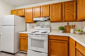Aiken apartment for rent - A white refrigerator and stove in a kitchen with wooden cabinets.