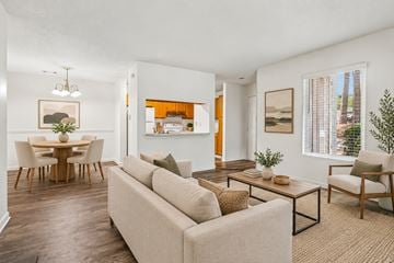 Aiken apartment for rent - A living room with a beige couch, a wooden dining table with chairs, and a painting on the wall.