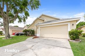 Kissimmee house for rent - a beige house with a driveway and a garage door
