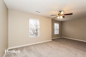 Charlotte house for rent - A spacious room with a ceiling fan and two windows.