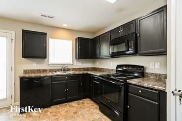 Charlotte house for rent - A kitchen with black cabinets and appliances.