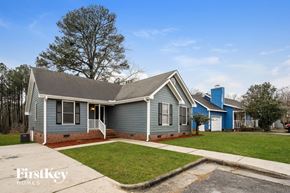 Raleigh house for rent - a blue house with a green lawn and a blue building behind it