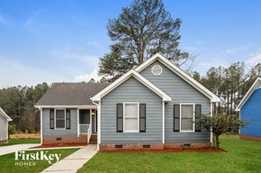 Raleigh house for rent - front view of a blue house with a lawn and trees