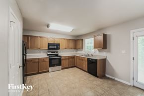 Charlotte house for rent - an empty kitchen with wooden cabinets and appliances and tiled floors