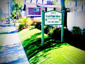 Escondido apartment for rent - A sign for Grand Palm Village Apartments stands in front of a house.