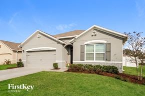 Kissimmee house for rent - A house with a garage and a tree in front.