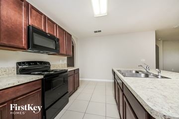 Kissimmee house for rent - A kitchen with a black stove top oven and microwave above a black dishwasher.
