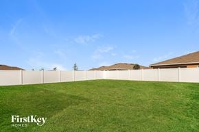 Kissimmee house for rent - A grassy field with a fence and houses in the background.