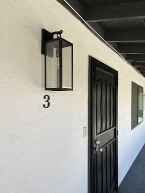 Bakersfield apartment for rent - the side of a building with a black door and a lantern on the wall