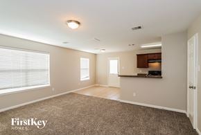 Richmond house for rent - A spacious room with a carpeted floor and a kitchenette in the background.