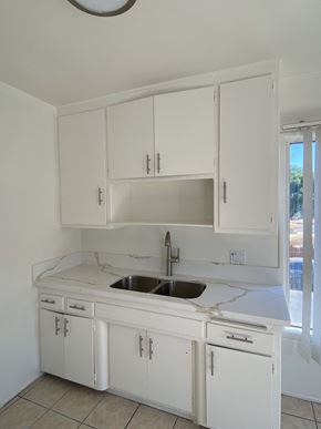 North Hollywood apartment for rent - an empty kitchen with white cabinets and a sink