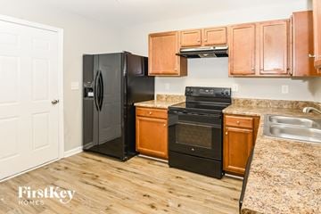 Charlotte house for rent - A kitchen with wooden cabinets and black appliances.