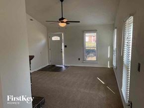 Charlotte house for rent - an empty living room with a ceiling fan and a door