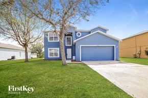 Poinciana house for rent - a blue house with a driveway and a blue garage door