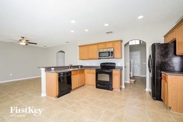 Poinciana house for rent - a large kitchen with black appliances and wooden cabinets