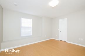 Poinciana house for rent - a bedroom with white walls and wood floors and a white door