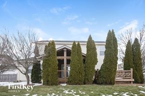 Brownsburg house for rent - A white house with a brown door and windows is surrounded by trees and has a snowy ground.