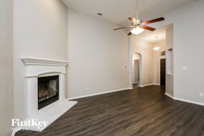 Haslet house for rent - A spacious room with a fireplace and a ceiling fan.