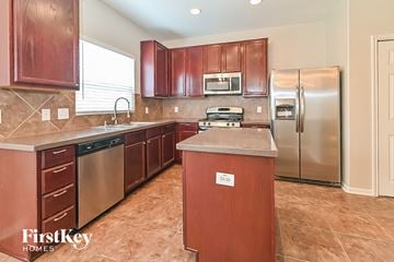 Spring house for rent - A kitchen with wooden cabinets and a stainless steel refrigerator.