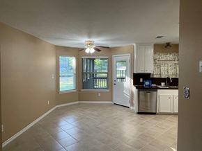 Trinity house for rent - an empty living room with a kitchen and a ceiling fan