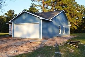 Trinity house for rent - A blue house with a white garage door is under construction.
