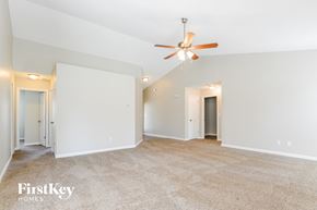 Charlotte house for rent - a spacious living room with white walls and a ceiling fan