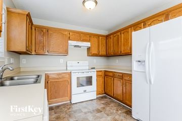 Charlotte house for rent - a kitchen with wooden cabinets and white appliances