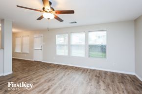 Burleson house for rent - an empty living room with a ceiling fan and windows