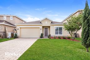 Kissimmee house for rent - a beige house with a lawn and a driveway