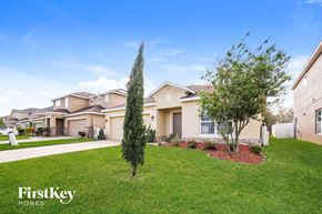 Kissimmee house for rent - a house with a yard and trees in front of it
