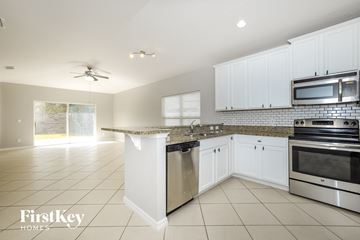 Kissimmee house for rent - a kitchen with white cabinets and stainless steel appliances