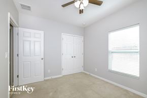 Kissimmee house for rent - a bedroom with two closets and a ceiling fan and a window
