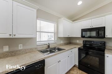 Lehigh Acres house for rent - A kitchen with white cabinets and black appliances.