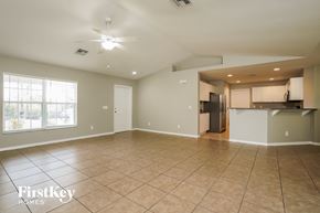 Lehigh Acres house for rent - A spacious empty room with a kitchen area in the background.