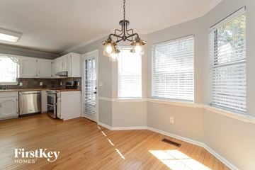 Alabaster house for rent - a kitchen with white cabinets and a wood floor and a chandelier