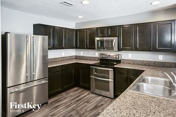 Whitestown house for rent - A kitchen with a stainless steel refrigerator and black cabinets.