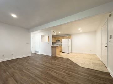 Provo apartment for rent - the living room and kitchen of a new home with white walls and wood flooring