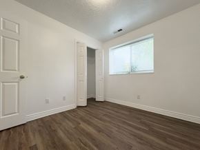 Provo apartment for rent - a bedroom with white walls and wood flooring and a window