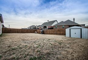 Aubrey house for rent - A backyard with a fence and a shed.