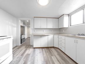 Provo apartment for rent - an empty kitchen with white cabinets and a wood floor