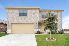 Fort Worth house for rent - A brick house with a tan garage door and a tree in front.