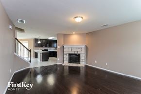 Fort Worth house for rent - A spacious living room with a fireplace and a kitchen in the background.
