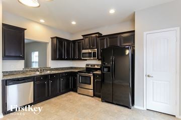 Royse City house for rent - a kitchen with black cabinets and stainless steel appliances