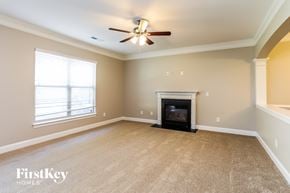 Mcleansville house for rent - A living room with a fireplace and a ceiling fan.