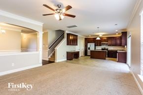 Mcleansville house for rent - A spacious living room with a carpeted floor and a ceiling fan.