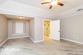 Arlington house for rent - A spacious room with a ceiling fan and a door leading to another room.