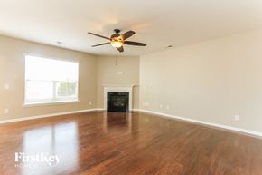 Huntersville house for rent - an empty living room with a ceiling fan and a fireplace