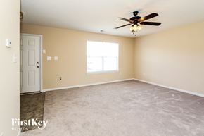 Charlotte house for rent - an empty living room with a ceiling fan and a window