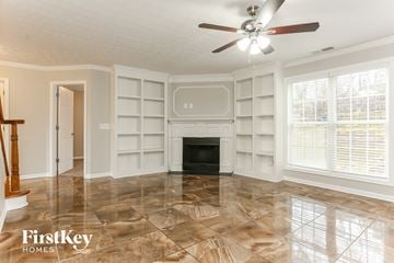 Lithonia house for rent - a living room with a fireplace and bookshelves and a ceiling fan