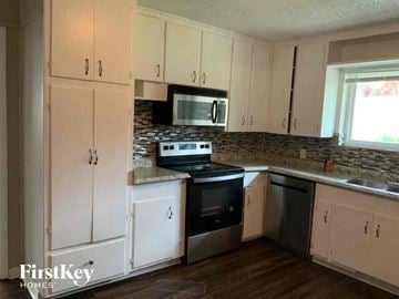 Fort Worth house for rent - a kitchen with white cabinets and a stove and a microwave